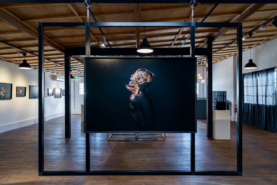 Suspended gallery frame holding a large portrait print, viewed through the surrounding frame structure